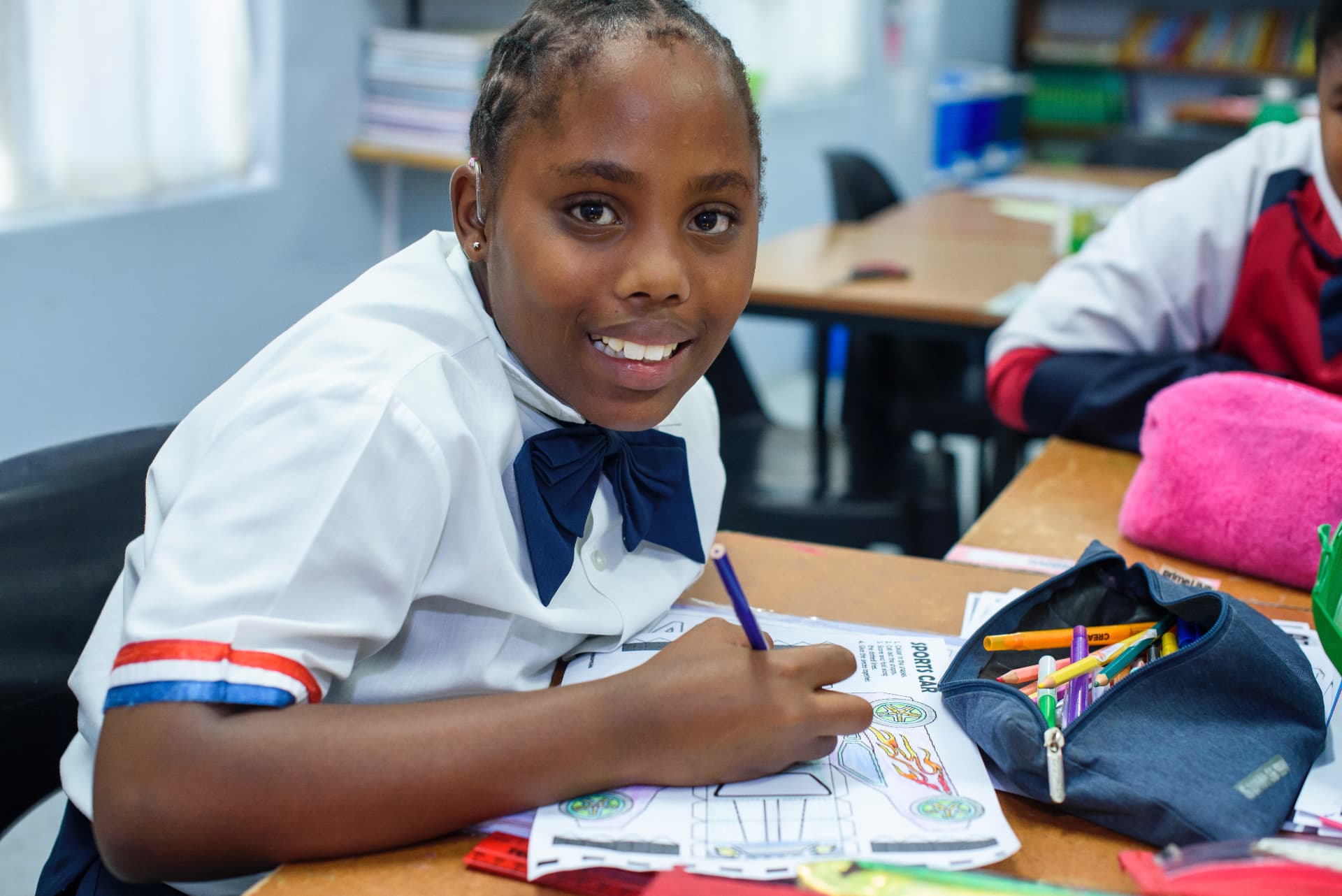 A pupil colouring a sports car design at her desk