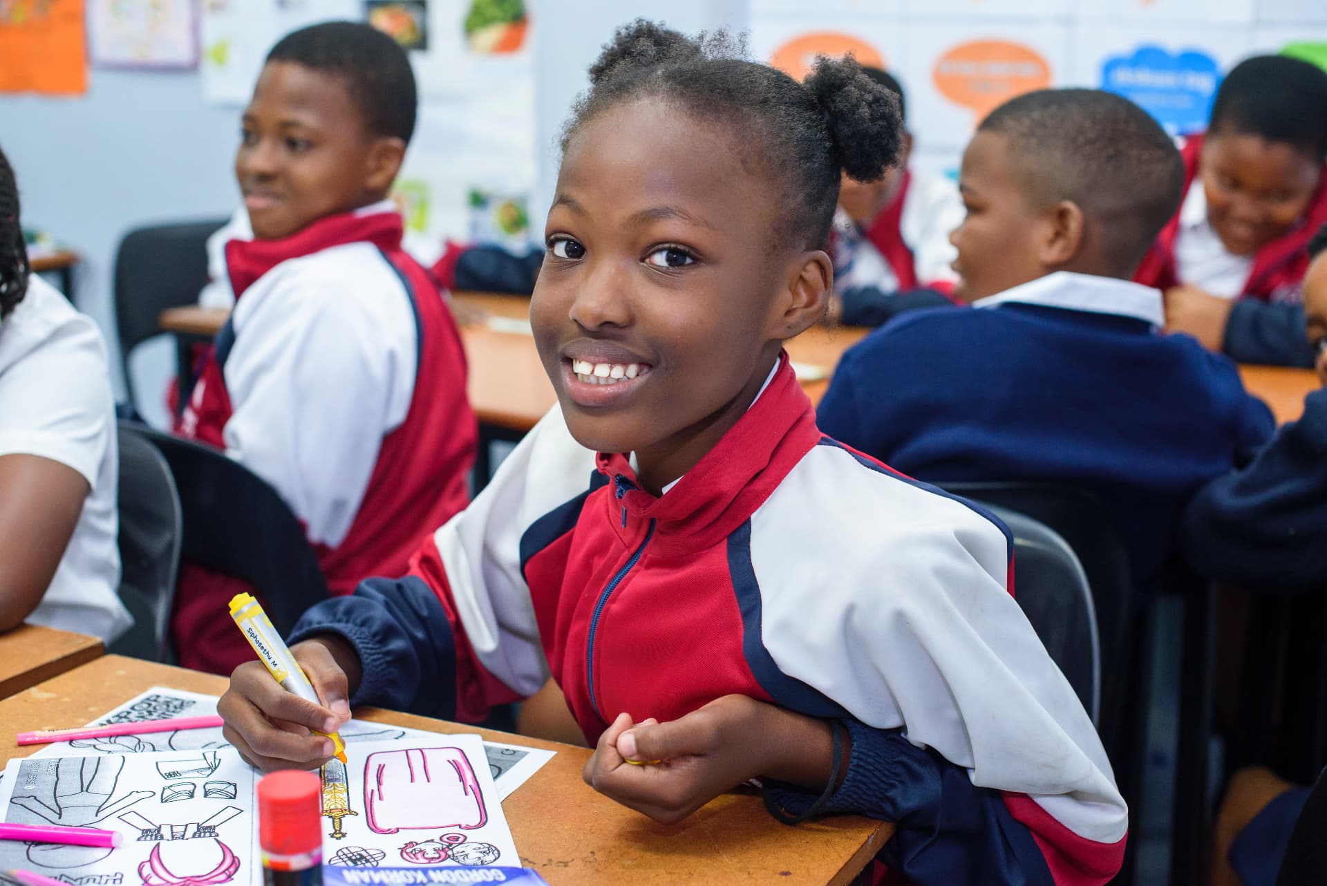 A pupil smiling while colouring a class project