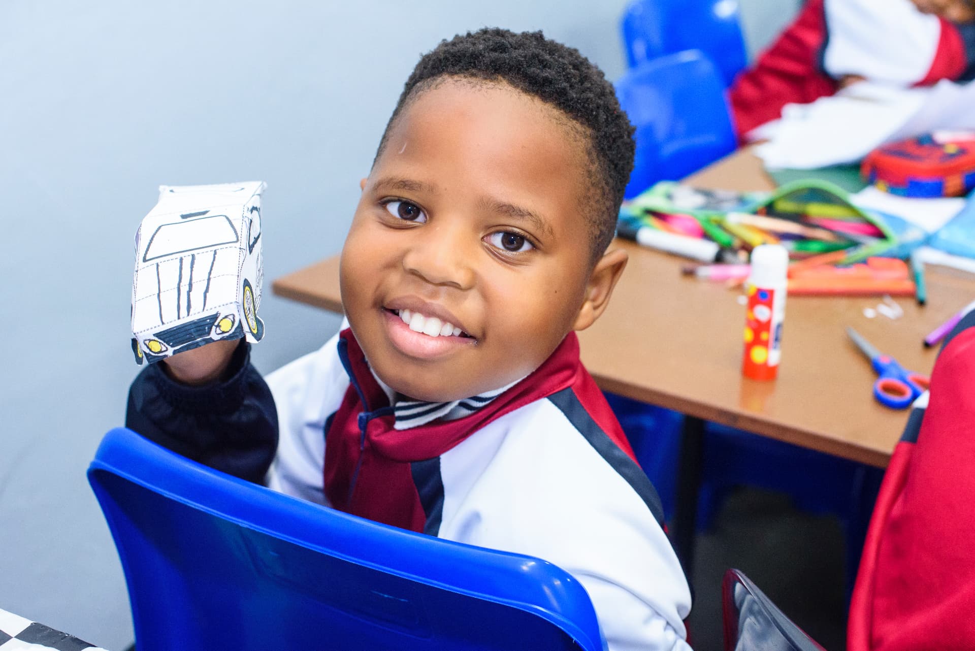 A young learner proudly holding up a paper craft model